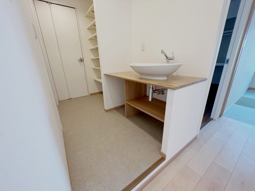 奥には造作した可動式収納棚とシンプルな洗面台。左手前の扉がトイレです。