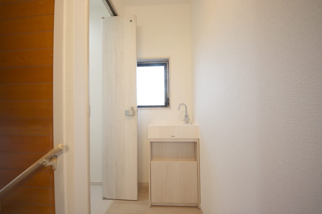 トイレ入口の前に手洗い器を設置。トイレの建具は折れ戸を設置。